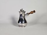 une cafetière en argent avec une poignée en bois sur une surface blanche