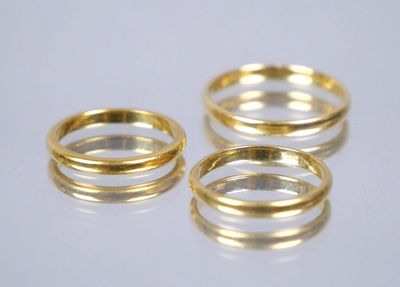 three gold rings on a white surface