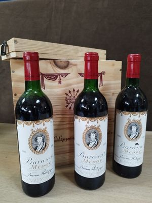 trois bouteilles de vin rouge sont posées devant une caisse en bois