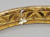 a close up of a gold bracelet on a white surface