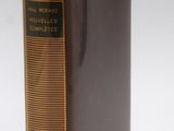 an old book sitting on top of a white table next to a yellow ribbon