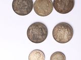 Plusieurs pièces de monnaie différentes sont alignées sur une surface blanche