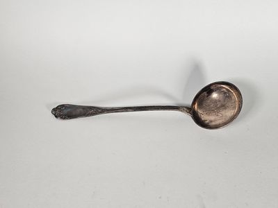 une vieille cuillère avec son manche, posée sur une surface blanche