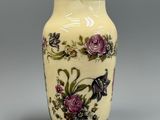 un vase jaune orné de fleurs violettes, posé sur un fond gris