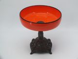 an orange bowl sitting on a stand on a white surface