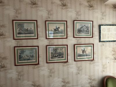 des tableaux accrochés au mur d'un salon où se trouve un fauteuil vert