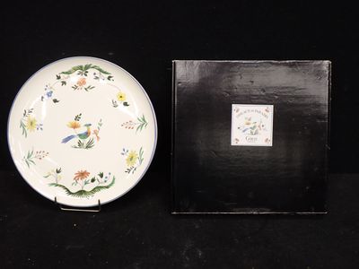 une assiette blanche sur laquelle est représenté un oiseau, à côté d'une boîte noire