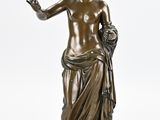an antique bronze statue of a woman holding a flower