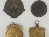 four medals of different shapes and sizes on a white surface