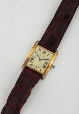 une photo d'une montre-bracelet posée sur une surface blanche, avec un bracelet marron
