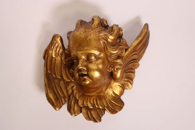 a gold statue of an angel on a white wall