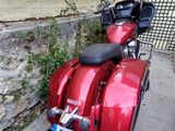 two red motorcycles parked next to each other on the sidewalk