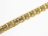 gros plan d'un bracelet en or sur une surface blanche