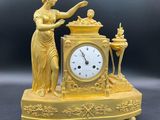 une horloge dorée représentant une femme tenant une bougie
