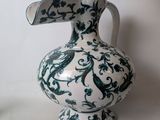 a white vase with a green and blue design on it