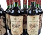 six bottles of wine are lined up in a row on a white surface