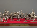 silver figurines of a group of men riding horses on a red carpet