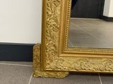 a large gold framed mirror on the floor in a room
