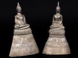 a pair of silver buddha statues sitting on top of a table