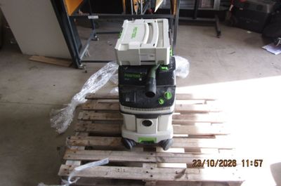 une photo d'un aspirateur vert et blanc posé sur une palette