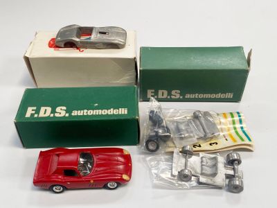 une petite voiture rouge posée à côté d'une boîte contenant d'autres petites voitures