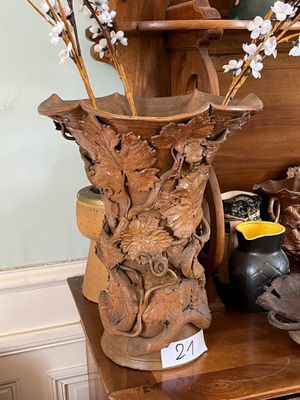 un vase en bois contenant des fleurs, posé sur une étagère