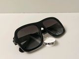 des lunettes de soleil noires posées sur une table blanche, avec une étiquette dessus