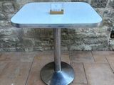 a small table with a glass top sitting on a brick floor
