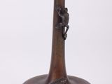 un vase en bronze orné d'un oiseau sur fond blanc