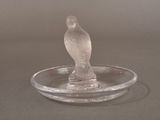 a glass bird sitting on top of a glass plate