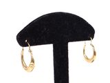 pair of gold hoop earrings on black velvet stand against a white background