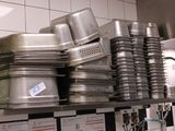 de nombreuses casseroles et poêles empilées sur une étagère dans une cuisine