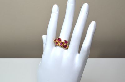 une paire de bagues rouges et dorées sur la main d'un mannequin blanc