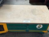 un chariot vert et jaune sur lequel se trouve une table en bois
