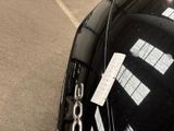 a black car parked in a parking lot with a sign attached to it