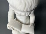 a statue of a boy reading a book on a table