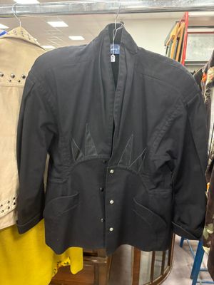 une veste noire suspendue à un portant dans un magasin de vêtements