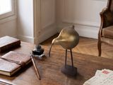 une statue d'oiseau posée sur une table, à côté d'un livre