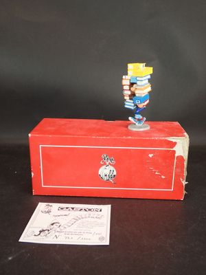 une petite figurine posée sur une boîte rouge