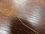 a gold chain on a wooden table with a gold necklace on it