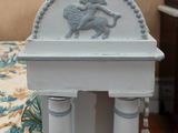 a small table with a statue on it in the corner of a room