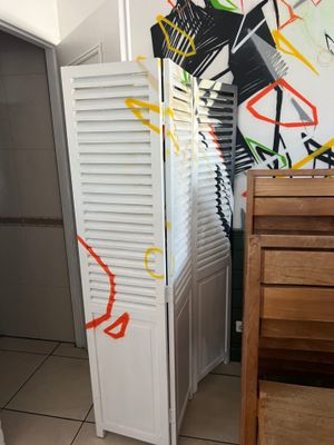 un graffiti sur le mur d'une salle de bains équipée d'un meuble blanc et d'une chaise en bois