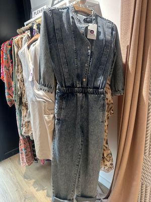 une combinaison en jean dans un magasin où des vêtements sont suspendus à un portemanteau