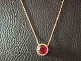 a necklace with a red stone on a black leather surface