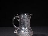 an old glass pitcher sitting on top of a black table