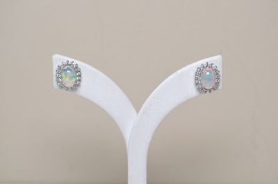 a pair of earrings that are on a white stand