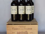 quatre bouteilles de vin rouge dans un coffret en bois posé sur une table