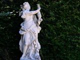a statue of a woman holding a bird in a garden