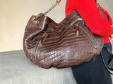 a woman sitting on a wall with a brown purse
