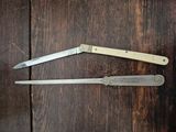 two knives sitting on a wooden table next to each other